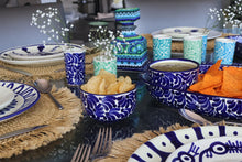 Load image into Gallery viewer, Decorative table setting with blue and white plates, bowls, and napkins on a glass table.
